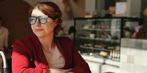 A Caucasian woman wearing a red blazer looking on the side while sitting down
